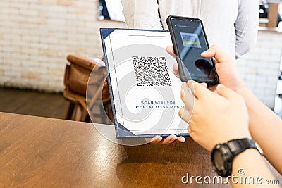 Person scanning contactless menu QR code with smartphone as new normal. Dummy code used Stock Photo