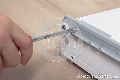 The person screws the bolt with a screwdriver when assembling furniture Stock Photo