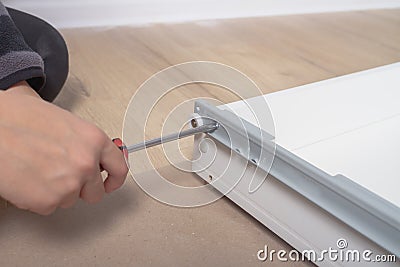 The person screws the bolt with a screwdriver when assembling furniture Stock Photo