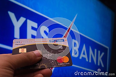 A person seen holding a credit card by Yes Bank infront of the yes bank board Editorial Stock Photo