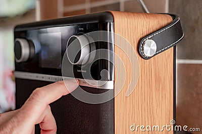 Person seen tuning a digital streaming radio in a kitchen area. Editorial Stock Photo