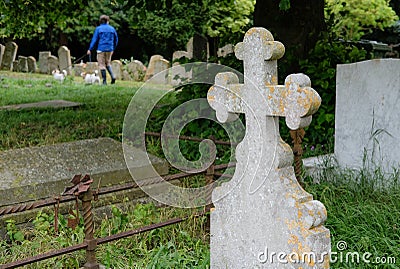 Person seen walking a couple of small dogs through old cemetery during the summer. Stock Photo