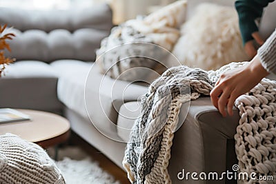 person setting up a cozy nook with a knit blanket on a sofa armrest Stock Photo