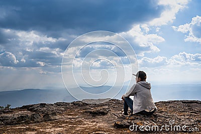 A person sitting on rocky mountain looking out at scenic natural view Stock Photo