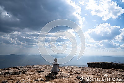 A person sitting on rocky mountain looking out at scenic natural view Stock Photo