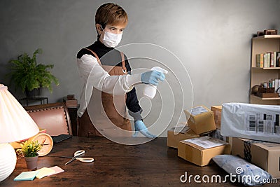 A person spraying disinfectant on parcels and boxes during coronavirus Covid-19 pandemic Stock Photo