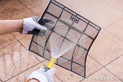 Person spraying water onto air conditioner filter to clean dust Stock Photo