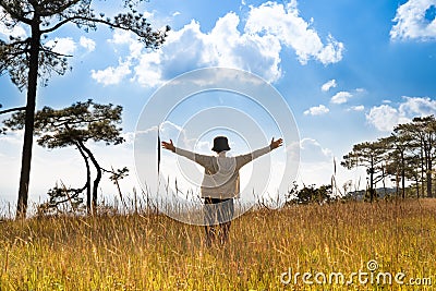 A person standing in large field enjoying the nature under beautiful blue sky Stock Photo