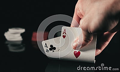 Person subtly raising poker cards on black background Stock Photo