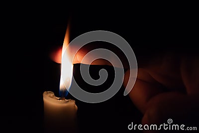 A person takes his finer into the candle flame. Burning in flame Stock Photo