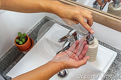 Person taking liquid soap to wash their hands in the bathroom Stock Photo