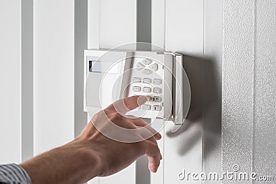 Person typing on keypad of home security alarm Stock Photo