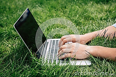 Person typing on laptop with blank screen outdoors Stock Photo