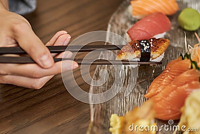 Person using chopsticks for eating sushi at a restaurant Stock Photo
