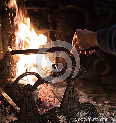 Person using a fire iron to stoke the flames Stock Photo