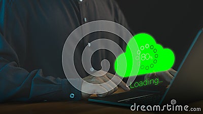 Person using a laptop computer with a glowing green cloud upload icon and loading progress bar Stock Photo