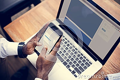 A person using a mobile phone and laptop Stock Photo