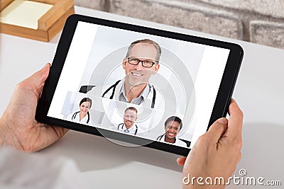 Person Videoconferencing With Doctors On Digital Tablet Stock Photo