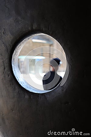 Person walks down the sidewalk framed by a sculpture. Bus shelter is seen in background Stock Photo