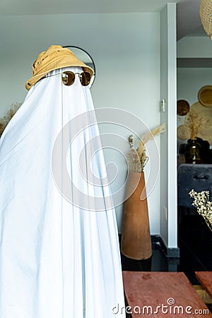 Person wearing a hat and black-rimmed sunglasses over a white cloth resembling a ghost Stock Photo