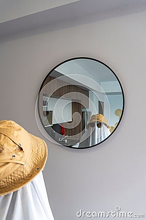 Person wearing a hat and sunglasses over a white cloth resembling a ghost looking into a mirror Stock Photo