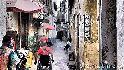 Person in wheelchair moving in narrow streets of Lamu Island Editorial Stock Photo
