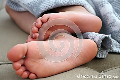 A person whose feet are lying outside the blanket, a sleeping person Stock Photo