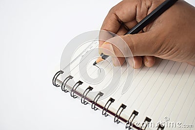 A person writing on a blank white notebook with a sharpened black pencil Stock Photo