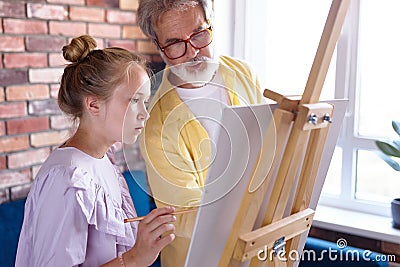 Personal art teacher teach little girl to draw on easel Stock Photo
