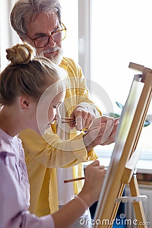 Personal art teacher teach little girl to draw on easel Stock Photo