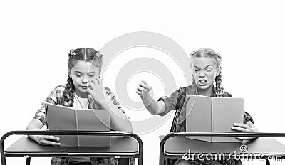 Personal attitude determines success. Acquiring knowledge. Small girls with books sit at desks reading lesson. Little Stock Photo