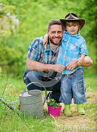 Personal example. Little helper in garden. Planting flowers. Growing plants. Take care of plants. Boy and father in Stock Photo