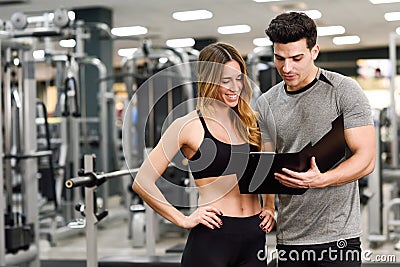 Personal trainer and client looking at her progress at the gym Stock Photo