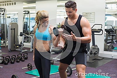 Personal trainer coaching female bodybuilder lifting dumbbell Stock Photo