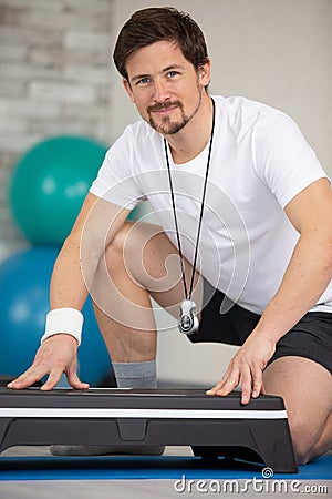 personal trainer crouching by step accessory Stock Photo