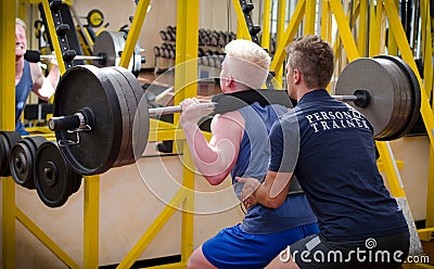 Personal trainer helping client in gym Stock Photo