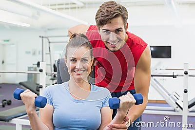 Personal trainer helping client lift dumbbells Stock Photo