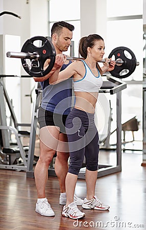 Personal trainer helping woman at gym Stock Photo