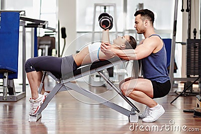 Personal trainer helping woman at gym Stock Photo