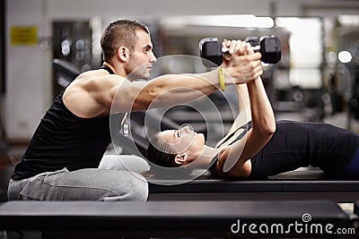 Personal trainer helping woman at gym Stock Photo