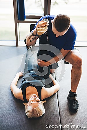 Personal trainer helping woman in stretching Stock Photo