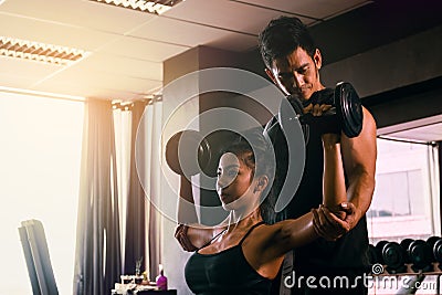 Personal trainer helping woman working lift heavy dumbbells two Stock Photo