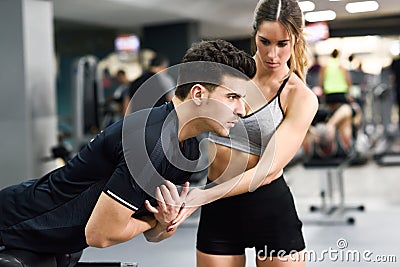 Personal trainer helping a young man lift weights Stock Photo