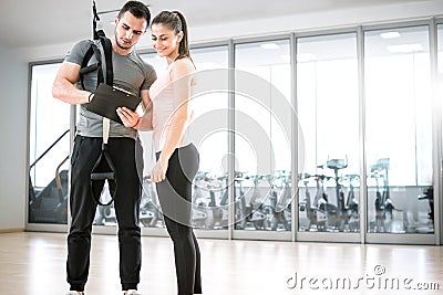 Personal trainer with suspension showing results to client. Stock Photo