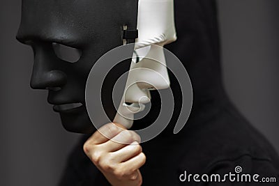 Personality mask, spy,hypocrisy, falsification of documents,hooded man with black white disguises Stock Photo