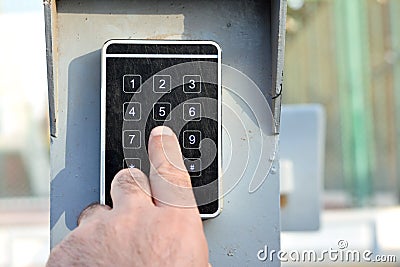 a persons hand pressing a password on a numerical keypad to lock or unlock an alarm system, opening garage gate for car entry, Stock Photo