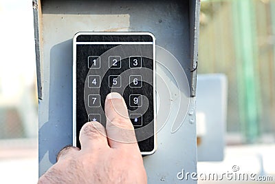 a persons hand pressing a password on a numerical keypad to lock or unlock an alarm system, opening garage gate for car entry, Stock Photo