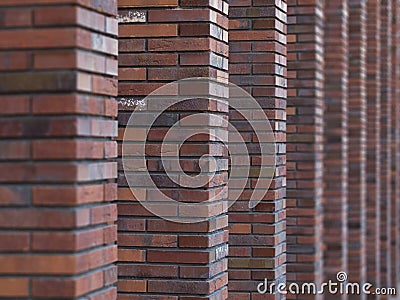 Perspective diagonal view on abstract brown red brick wall with columns with blured background. Architecture element brown brick w Stock Photo