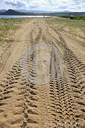 Perspective of tyre tracks on sandy beach Stock Photo