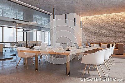 Perspective view on light wooden conference table with modern laptops surrounded by white chairs in sunlit meeting room with brick Stock Photo